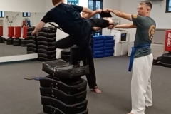 A Black Belt teen executes a perfect running jump side kick board break over obstacles. A Black Belt teen executes a perfect running jump side kick board break over obstacles.