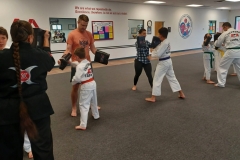 Chief Master LK keeps an eye on the parent/kid pairings while holding targets during a punching round! 