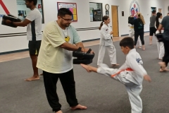Dad holds the targets while his son practices a front kick during the cardio round!