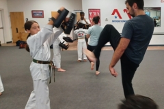A daughter challenging her father to kick higher during the cardio drill! 