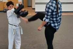 A KFMA Tiger holding targets while his Mom practices her front kick!