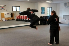 Adults practicing running jump side kicks during a Family class!