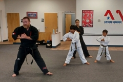 Adult and Teen Assistant Instructors working with KFMA Kids on their traditional Songahm form. 