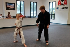 Black Belt assistant working with a high-rank color belt kid on her traditional Songahm Taekwondo form.