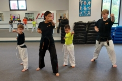 Black Belt Teens assisting in the KFMA Family class working with White Belts on Taekwondo Forms.