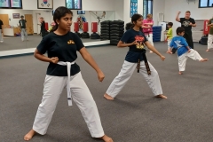 Black Belt Teen assisting in the KFMA Family class working with a White Belt on Taekwondo Forms.
