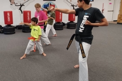 Black Belt Teens assisting in the KFMA Family class working with Low Rank Kids on Taekwondo Forms.
