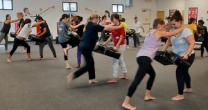 Women and teens practicing knee strikes at KFMA Women's self-defense seminar Tampa