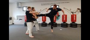 KFMA Black Belt Adult breaking boards with the Jump Reverse Side Kick of Taekwondo.