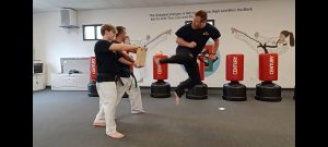 KFMA Black Belt Adult showing the proper chamber of the leg when breaking boards with the Jump Reverse Side Kick of Taekwondo.