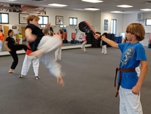 Black Belt Teen at KFMA practicing a Butterfly Kick on a focus paddle.