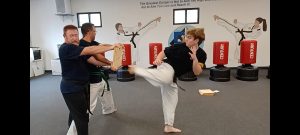 KFMA Black Belt Adult showing the proper chamber of the leg when breaking boards with the Reverse Side Kick of Taekwondo.